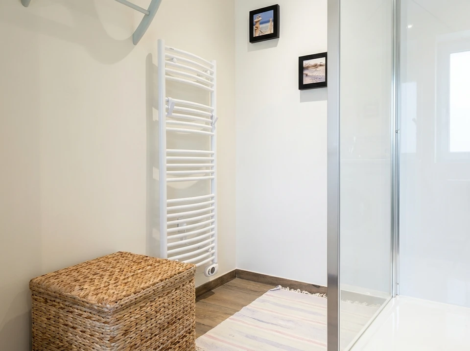 Photographie d'un chantier de rénovation montrant plusieurs professionnels en tenue de travail professionnelle coordonnée intervenant simultanément sur différents systèmes : un électricien installant un tableau électrique mural, un chauffagiste effectuant la mise en place d'une pompe à chaleur, et un plombier raccordant des tuyauteries. La scène doit montrer la collaboration et la coordination sur un même espace intérieur (cuisine ou salon en rénovation), avec des équipements modernes visibles, illustrant ainsi la capacité de l'entreprise à gérer plusieurs corps d'état sous une même coordination.